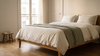 Chambre slow living à la lumière du soir, lit en percale lavée blanc cassé et plaid en maille vert sauge