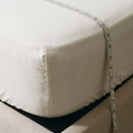 Angle de matelas épais avec un drap-housse en coton blanc et un mètre ruban mesurant la hauteur de bonnet