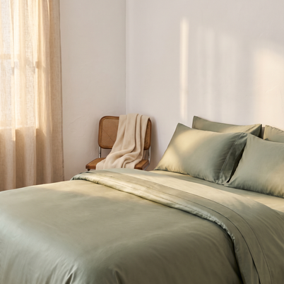 Housse de couette en coton égyptien vert sauge sur un lit, lumière dorée, Noctua Paris