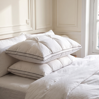 Oreillers plumes et duvet d'oie blancs avec passepoil empilés sur un lit, Noctua Paris