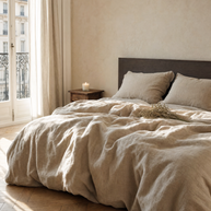 Parure de lit en lin lavé naturel Noctua Paris sur un lit dans une chambre parisienne, lumière du matin