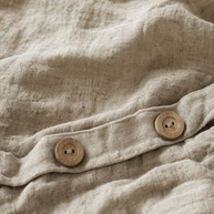 Gros plan sur le tissage irrégulier du lin lavé Noctua Paris et les boutons en bois naturel