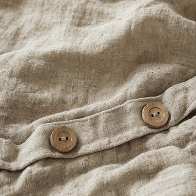 Gros plan sur le tissage irrégulier du lin lavé Noctua Paris et les boutons en bois naturel