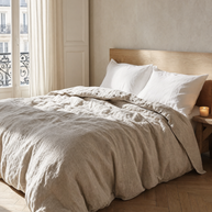 Housse de couette en lin lavé naturel Noctua Paris sur un lit dans une chambre parisienne, lumière du matin