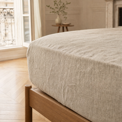 Drap-housse en lin lavé naturel Noctua Paris tendu sur un matelas, coin de lit en chêne clair
