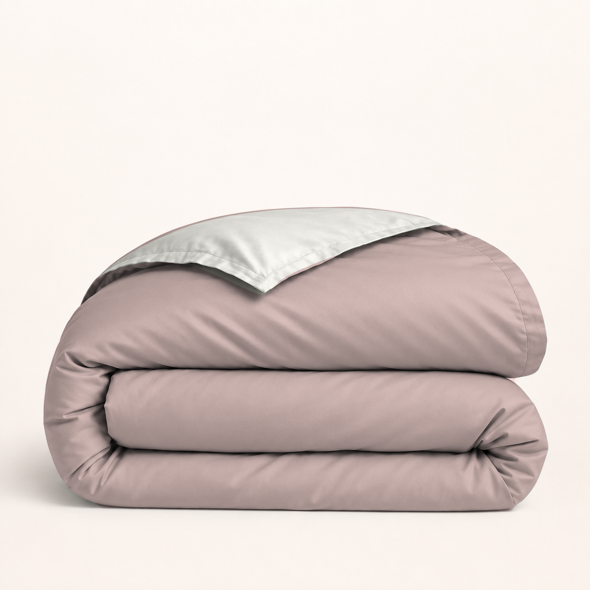 Housse de couette en coton égyptien rose champagne — housse seule pliée, revers champagne, fond ivoire — Noctua Paris.