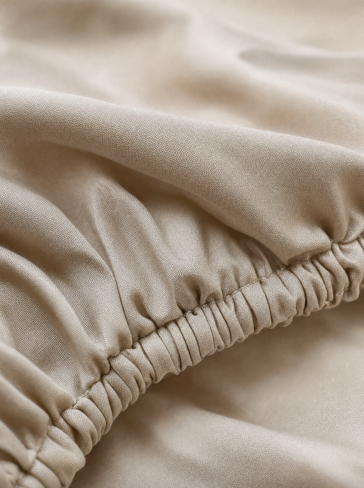 Gros plan macro sur l'élastique et le tissage sateen du drap-housse coton égyptien Noctua Paris