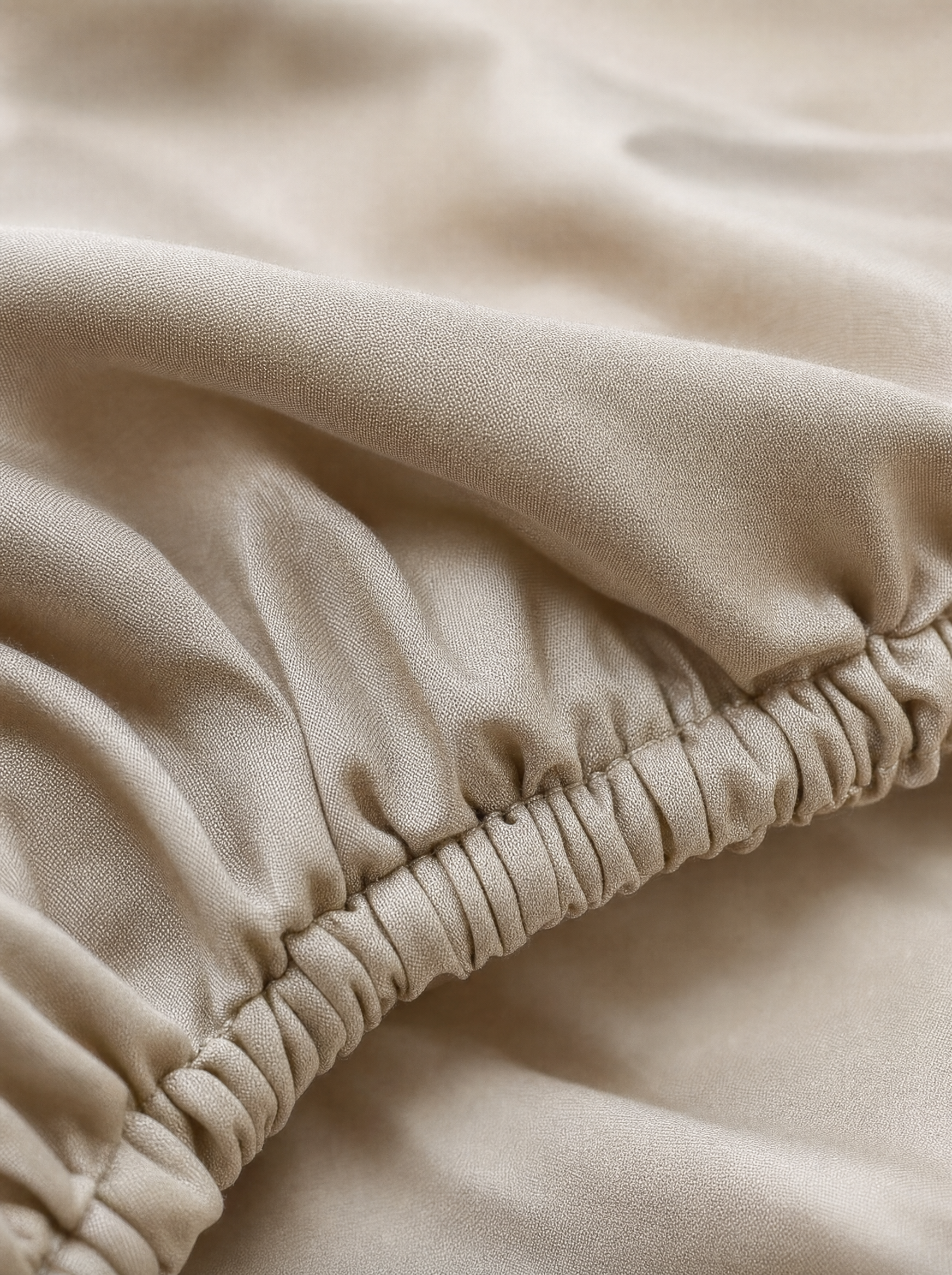 Gros plan macro sur l'élastique et le tissage sateen du drap-housse coton égyptien Noctua Paris
