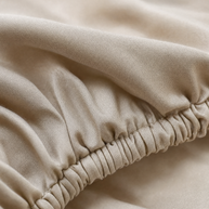 Gros plan macro sur l'élastique et le tissage sateen du drap-housse coton égyptien Noctua Paris