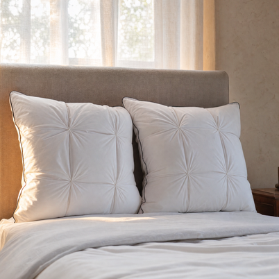 Oreillers plumes et duvet d'oie Noctua Paris contre une tête de lit en lin, lumière à contre-jour