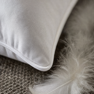 Gros plan macro sur le passepoil coton et une plume de duvet d'oie de l'oreiller Noctua Paris