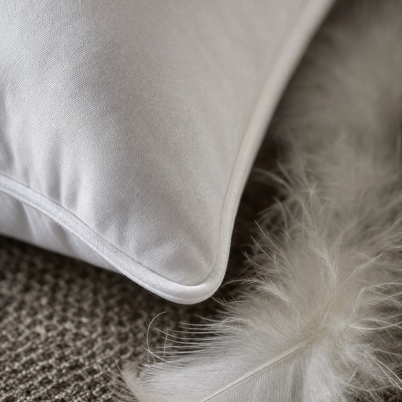 Gros plan macro sur le passepoil coton et une plume de duvet d'oie de l'oreiller Noctua Paris