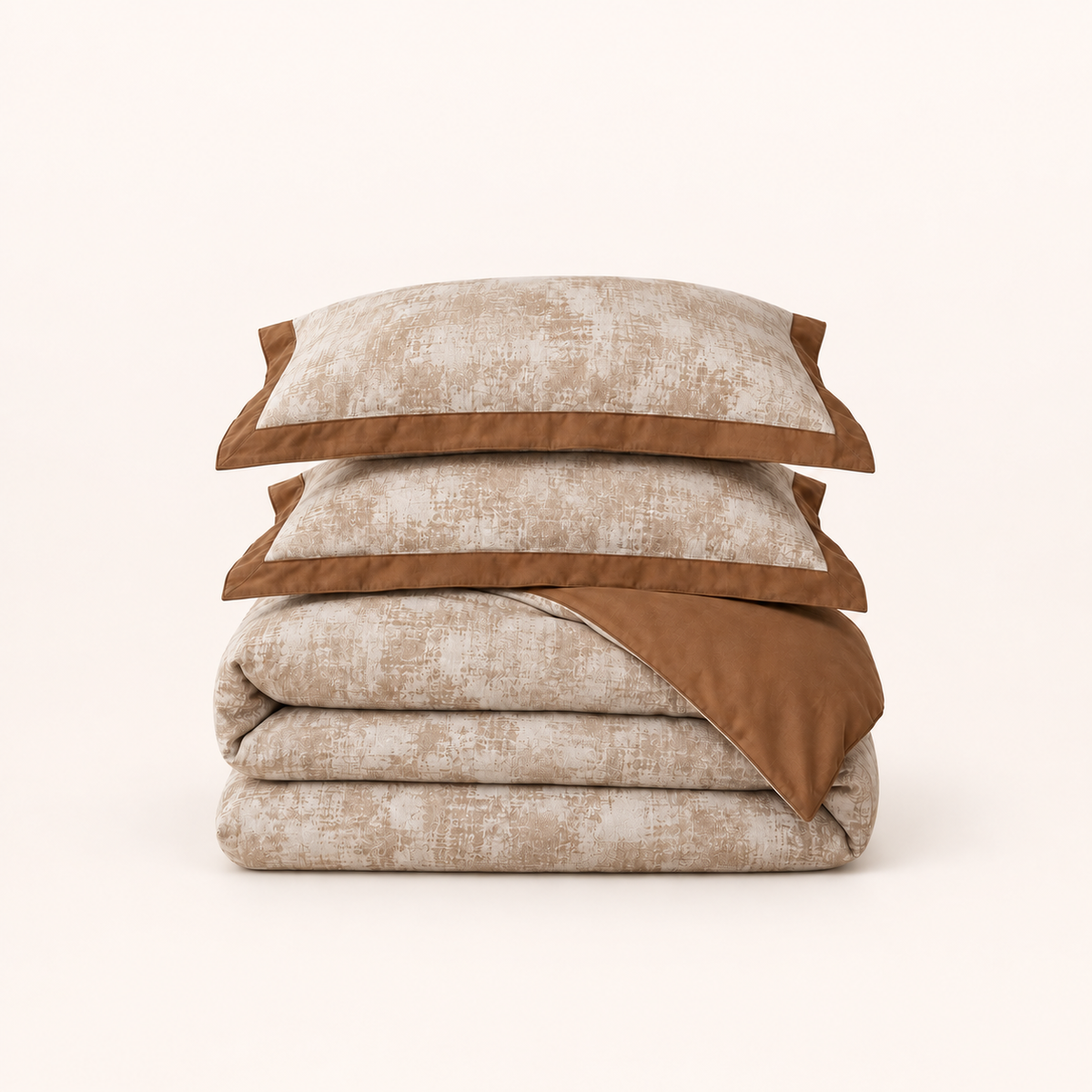 Noctua Paris — Parure de lit en gaze de coton caramel, deux taies à bordure unie et housse pliée, sur fond ivoire.