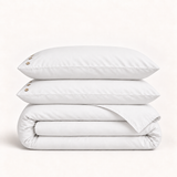 Parure de lit en percale de coton blanche — deux taies et une housse pliée sur fond ivoire — Noctua Paris