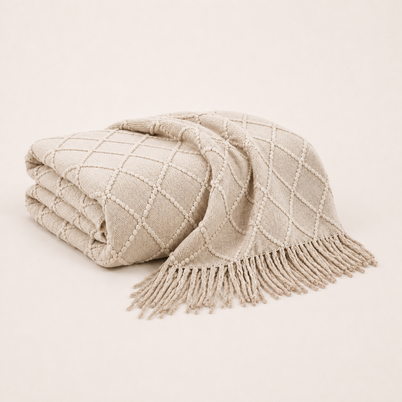 Plaid en maille à franges crème plié sur fond blanc chaud Noctua Paris